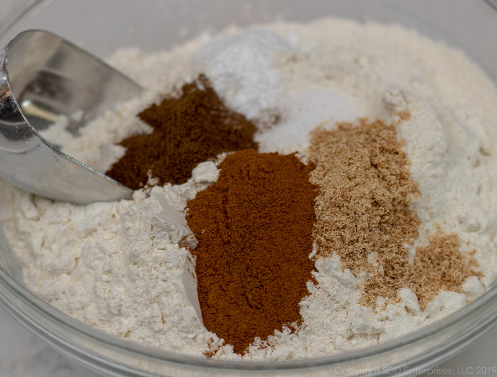 spices added to all-purpose flour in a glass bowl for fruitcake