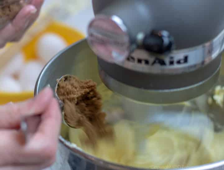 brown sugar being added to mixing bowl for fruitcake