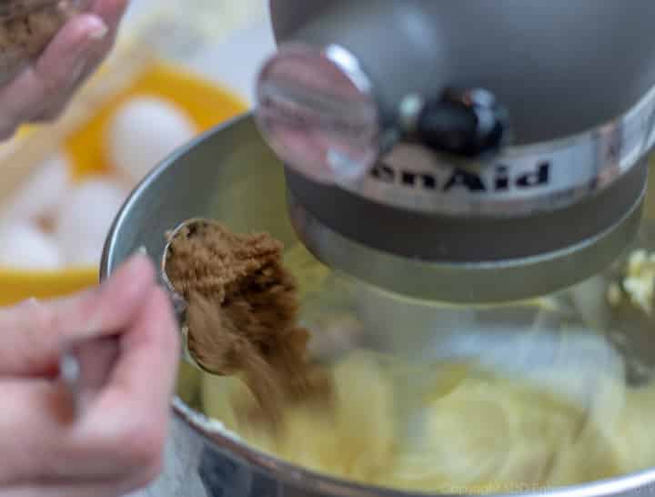 Brown sugar being added to mixing bowl for fruitcake.