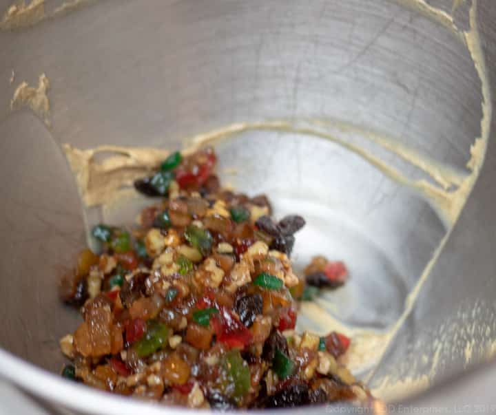 Mixed fruit in batter in a mixing bowl for fruitcake.