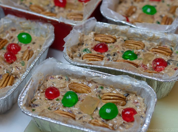 Filled fruitcake pans with fruit and nut garnish.