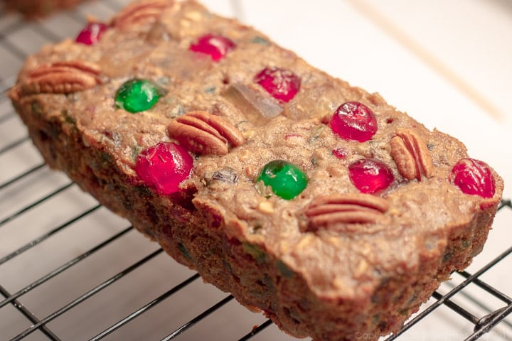 A small baked fruitcake on a cooling rack.