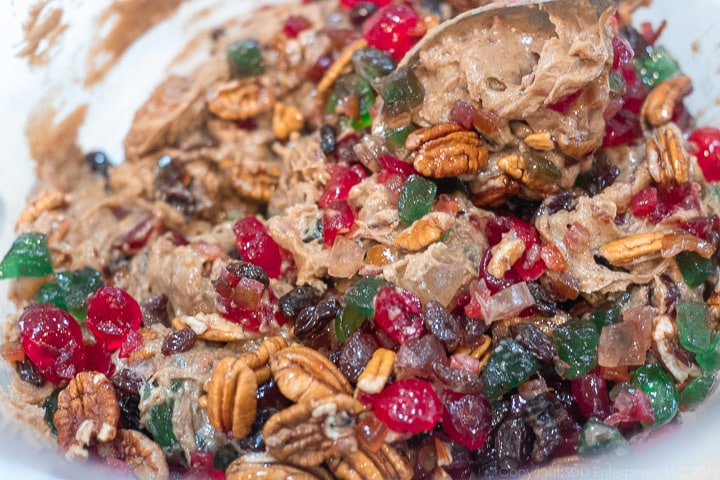 blending the candied fruit with the batter in a bowl for fruitcake cookies