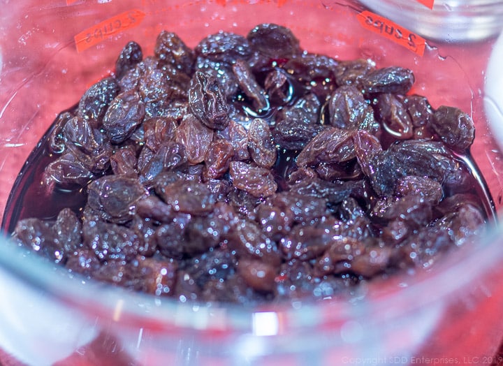 dark raisins marinading in cherry randy in a measuring cup