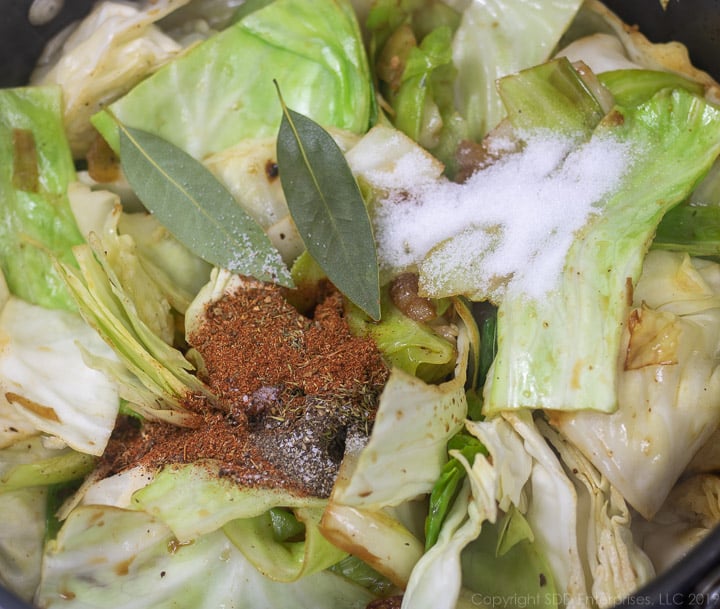 herbs and spices added to cabbage in a dutch oven for smothered cabbage