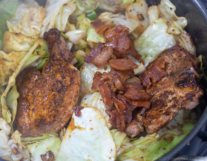 pork chops and bacon being added to cabbage in dutch oven for smothered cabbage