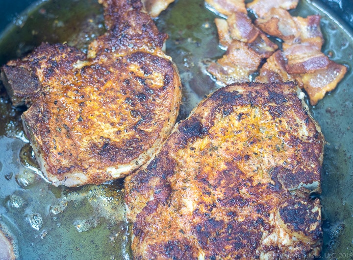 pork chops and bacon frying in a dutch oven for smothered cabbage