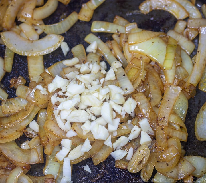 chopped garlic and sliced onions frying in dutch oven for smothered cabbage