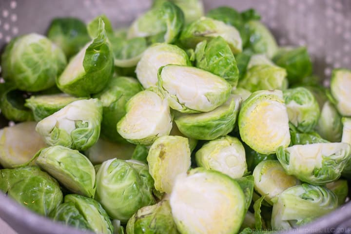 cleaned brussels sprouts sliced in half in a colander