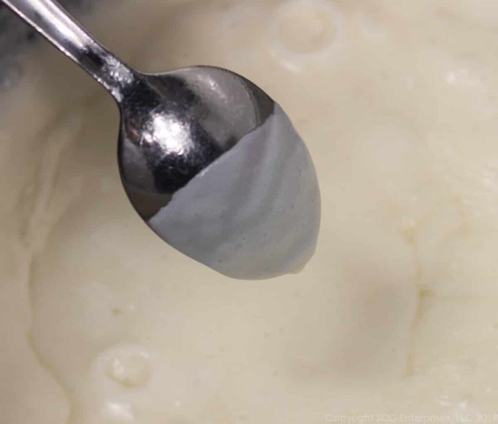 thickened bechamek sauce for macaroni and cheese with a sauce coated spoon