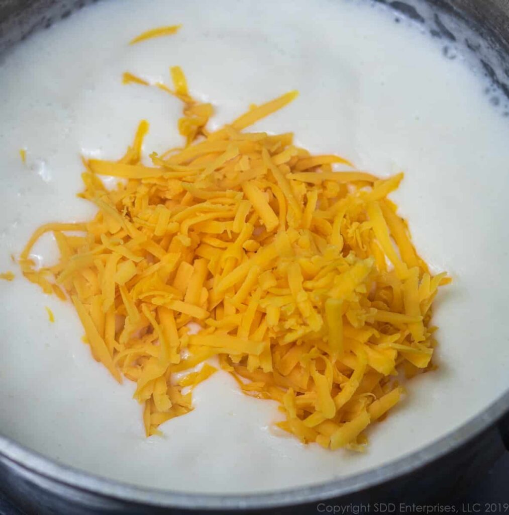 grated cheddar cheese added to the bechamel sauce in a sauce pan