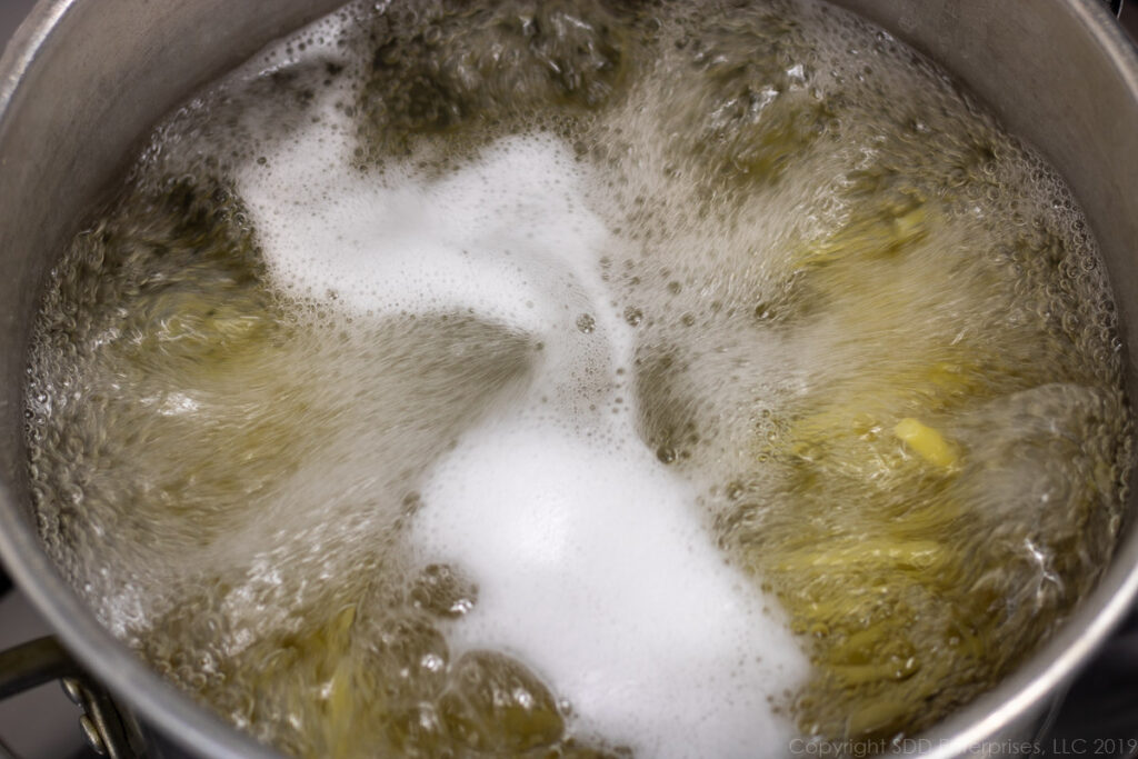 long macaroni noodles boiling in salted water for macaroni and cheese