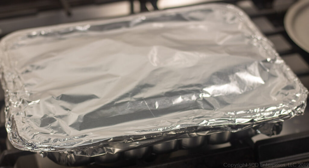 pan of macaroni and cheese covered in aluminum foil ready for the oven