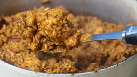 a spoonful of creole jambalaya held over a dutch oven of creole jambalaya