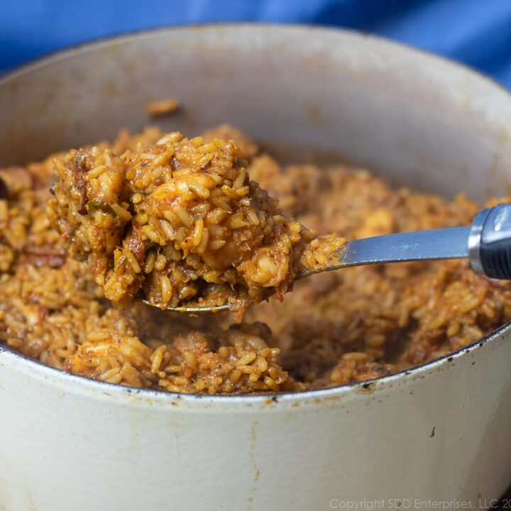 a spoonful of creole jambalaya held over a dutch oven of creole jambalaya