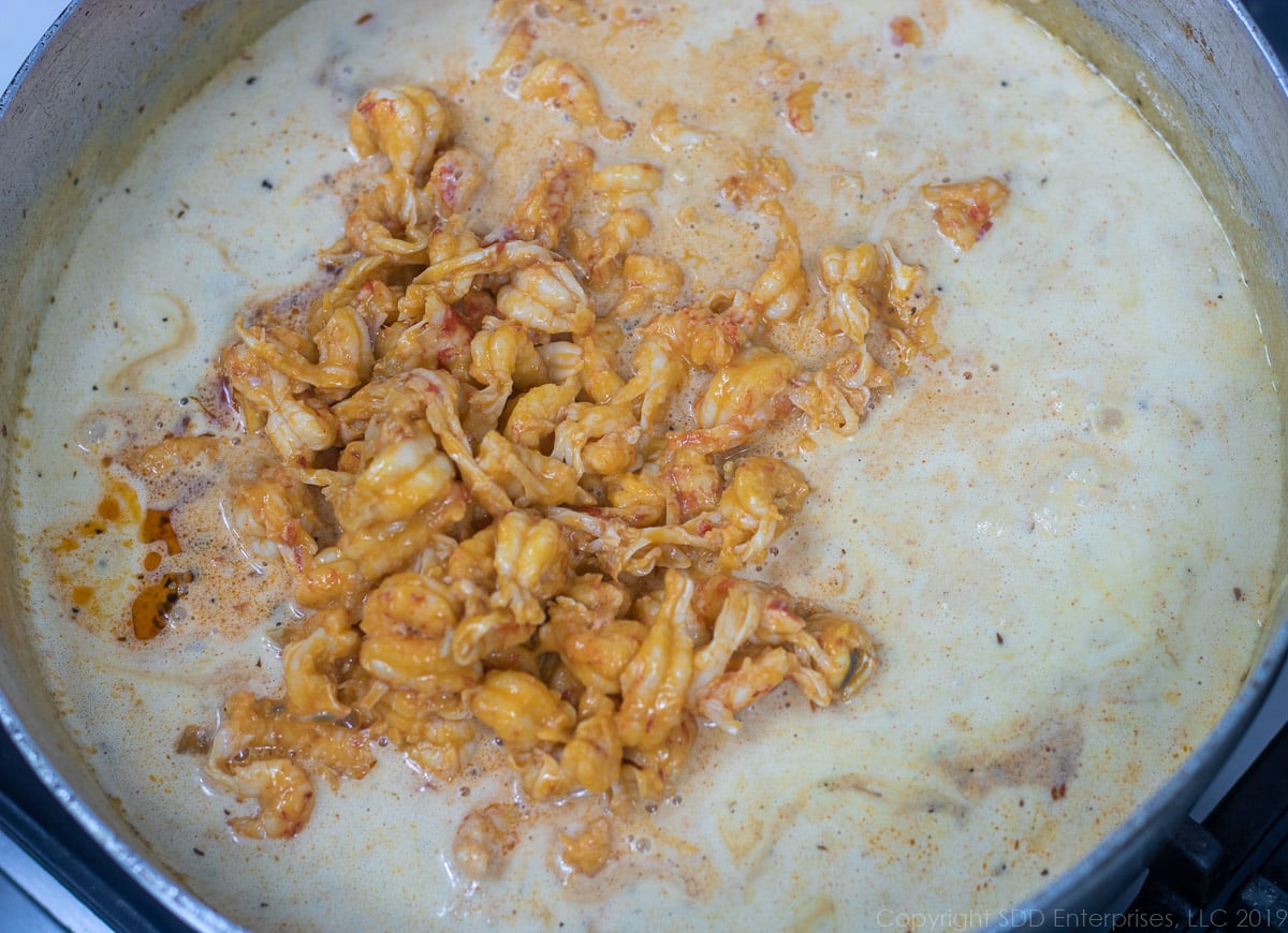 crawfish tails added to the heavy cream in a frying pan