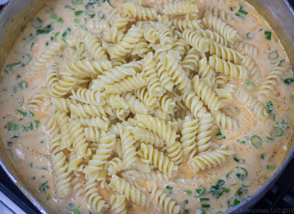 cooked rotini pasta added to crawfish in cream sauce