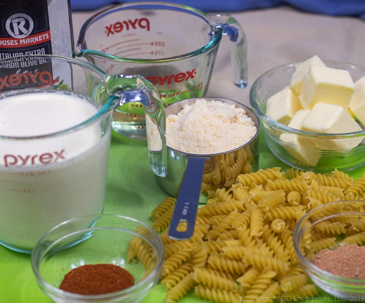 uncooked pasta, parmesan cheese, butter, cream, wine and spices on a cutting board