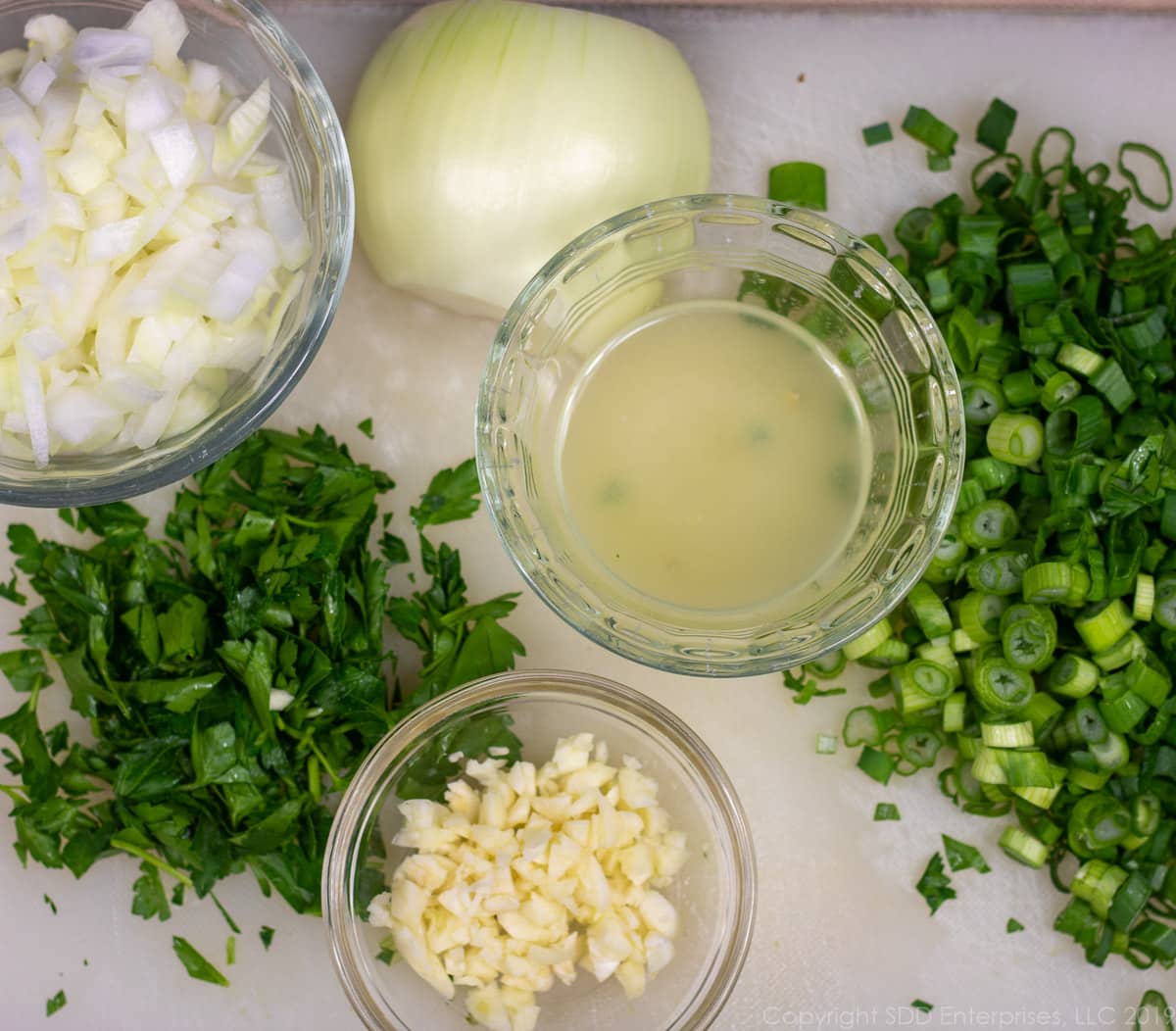 chopped onions, parsley, garlic and lemon juice on a cutting board