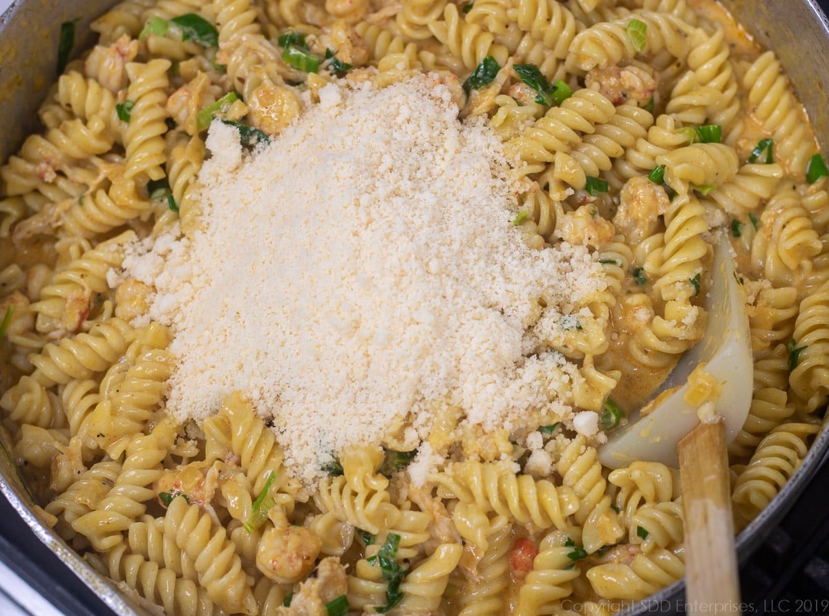 grated parmesan cheese added to the crawfish monica in a frying pan