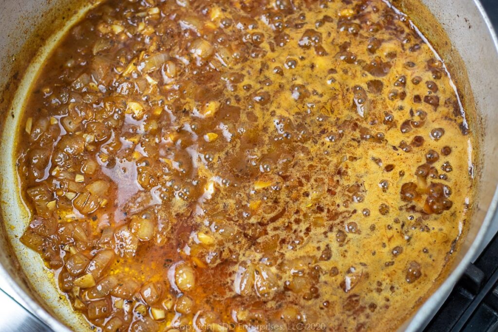 simmering stock in a frying pan with shallots and spices