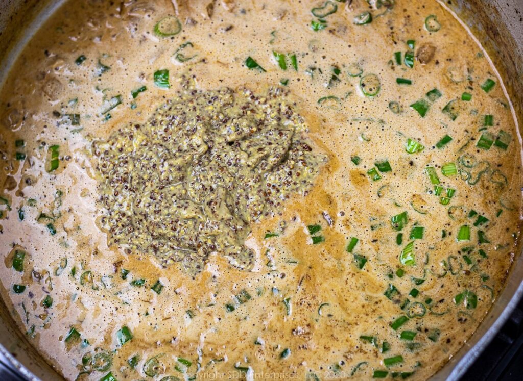 creole mustard and green onions in sauce in a frying pan