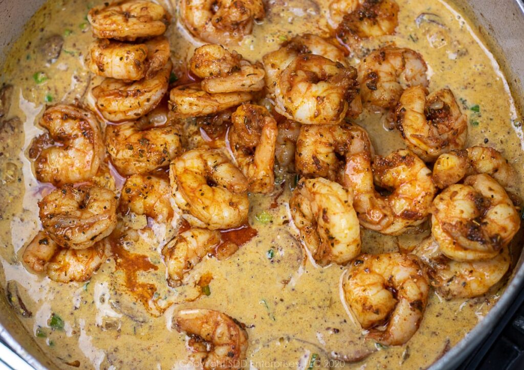 sauteed shrimp added to sausage and sauce in a frying pan