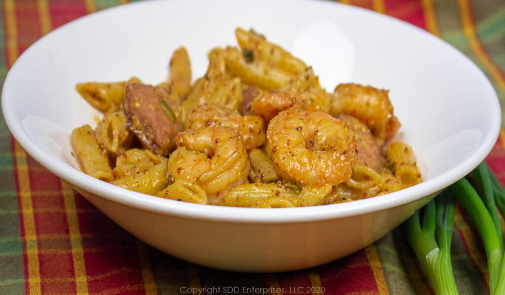 shrimp and sausage with pasta in sauce in a white bowl