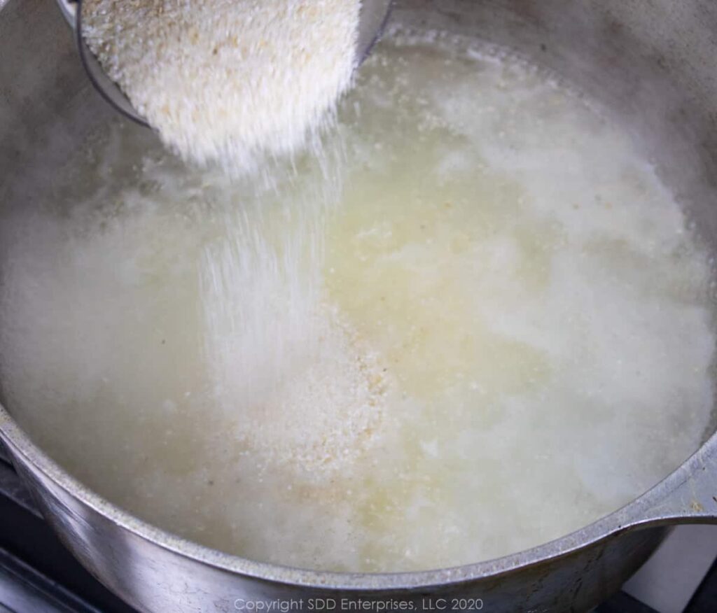 adding uncooked grits to boiling water