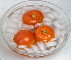 three tomatoes in an ice bath