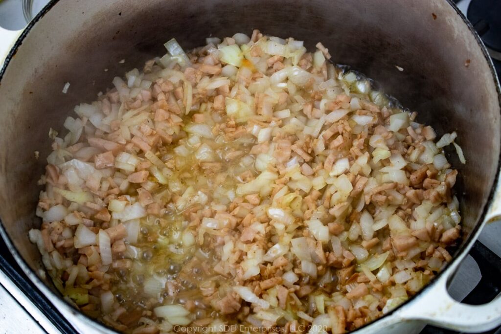 onions added to ham and bacon grease in a dutch oven