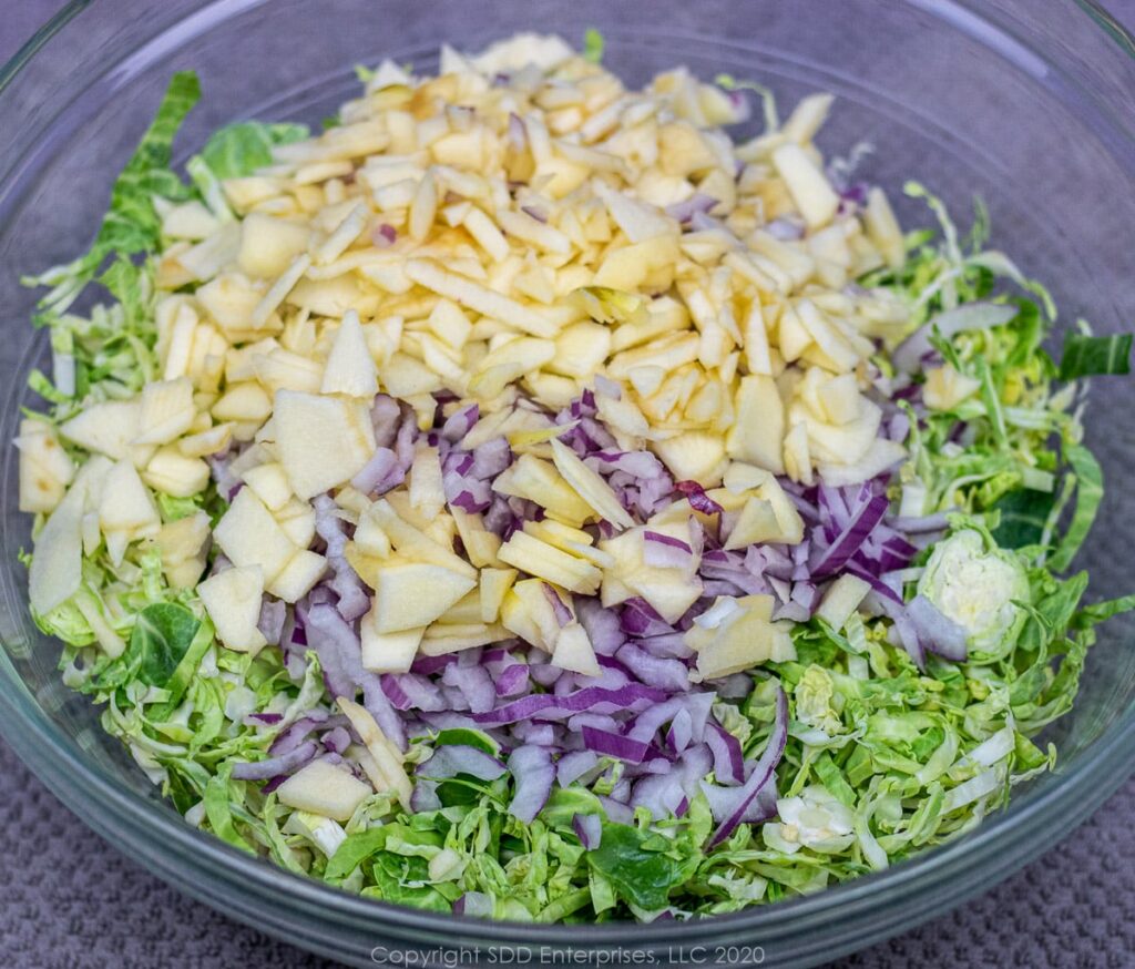 chopped ingredients for brussels sprout slaw in a mixing bowl