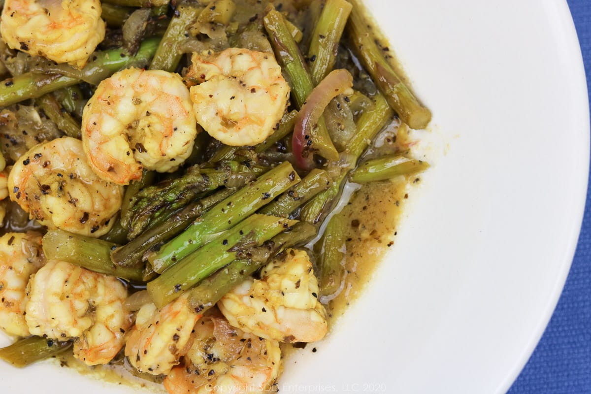 sauteed shrimp with asparagus in a white bowl