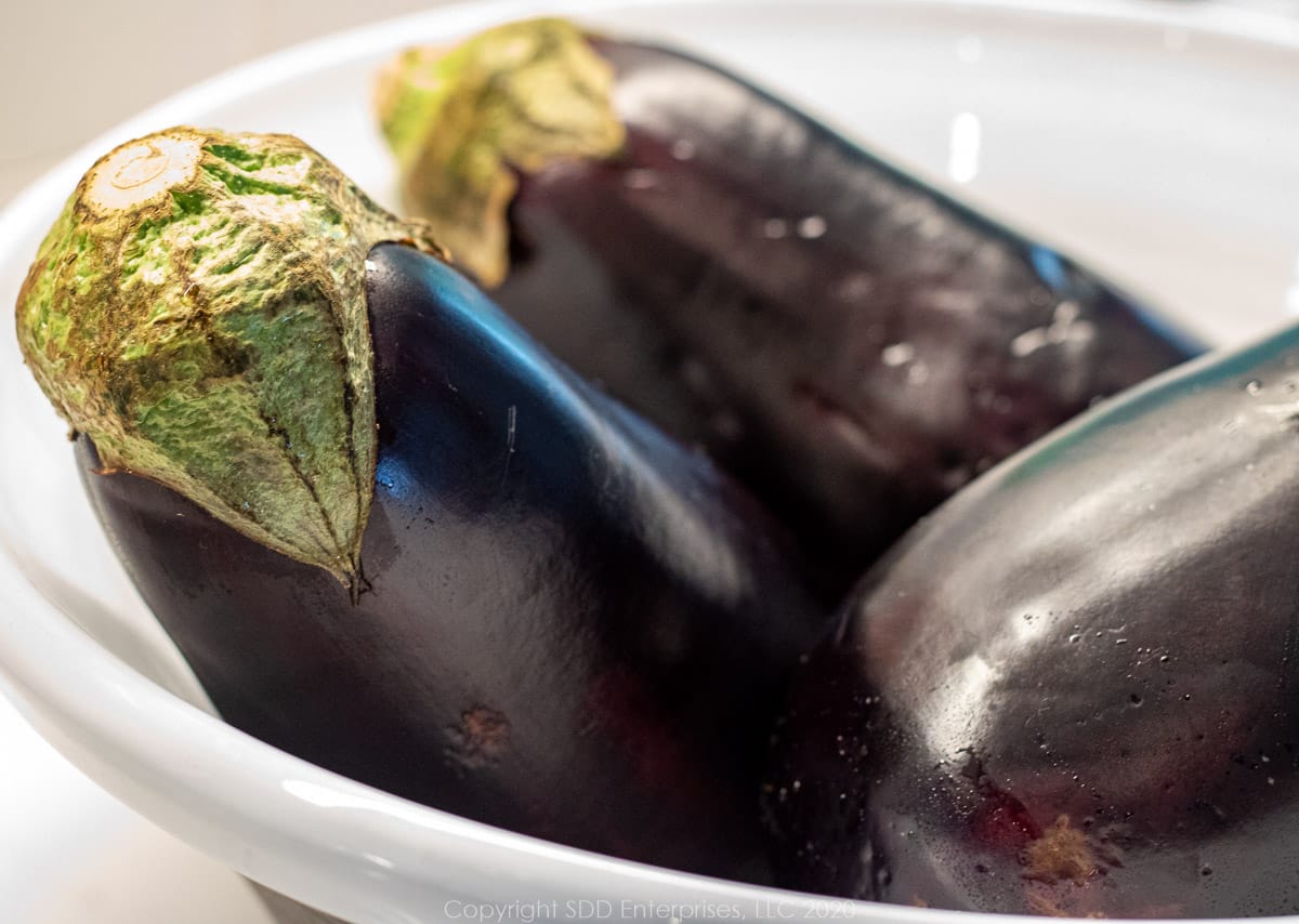 three purple eggplant in a white owl