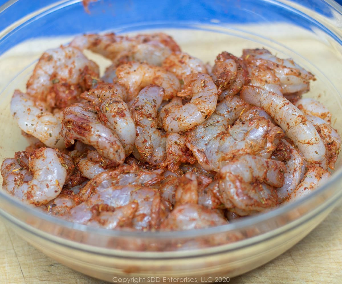 uncooked shrimp with creole seasoning in a glass bowl