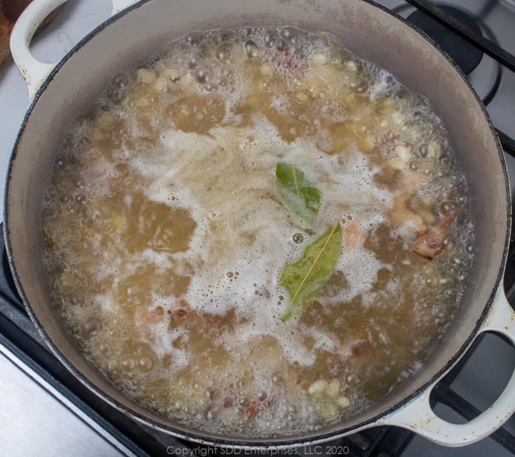 navy beans and meats simmering in a dutch oven