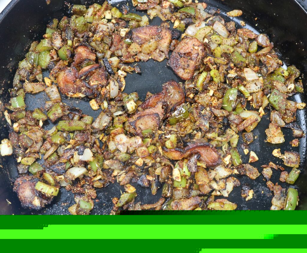 cast iron skillet with sauteeing trinity and garlic in a cast iron skillet