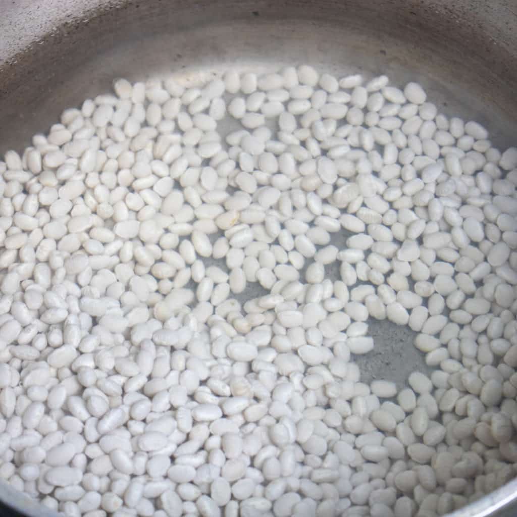 navy beans soaking in water in a dutch oven