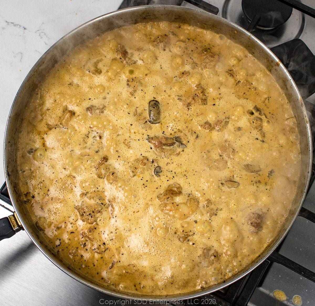 cream added to frying pan with mushroom, onions and tomatoes