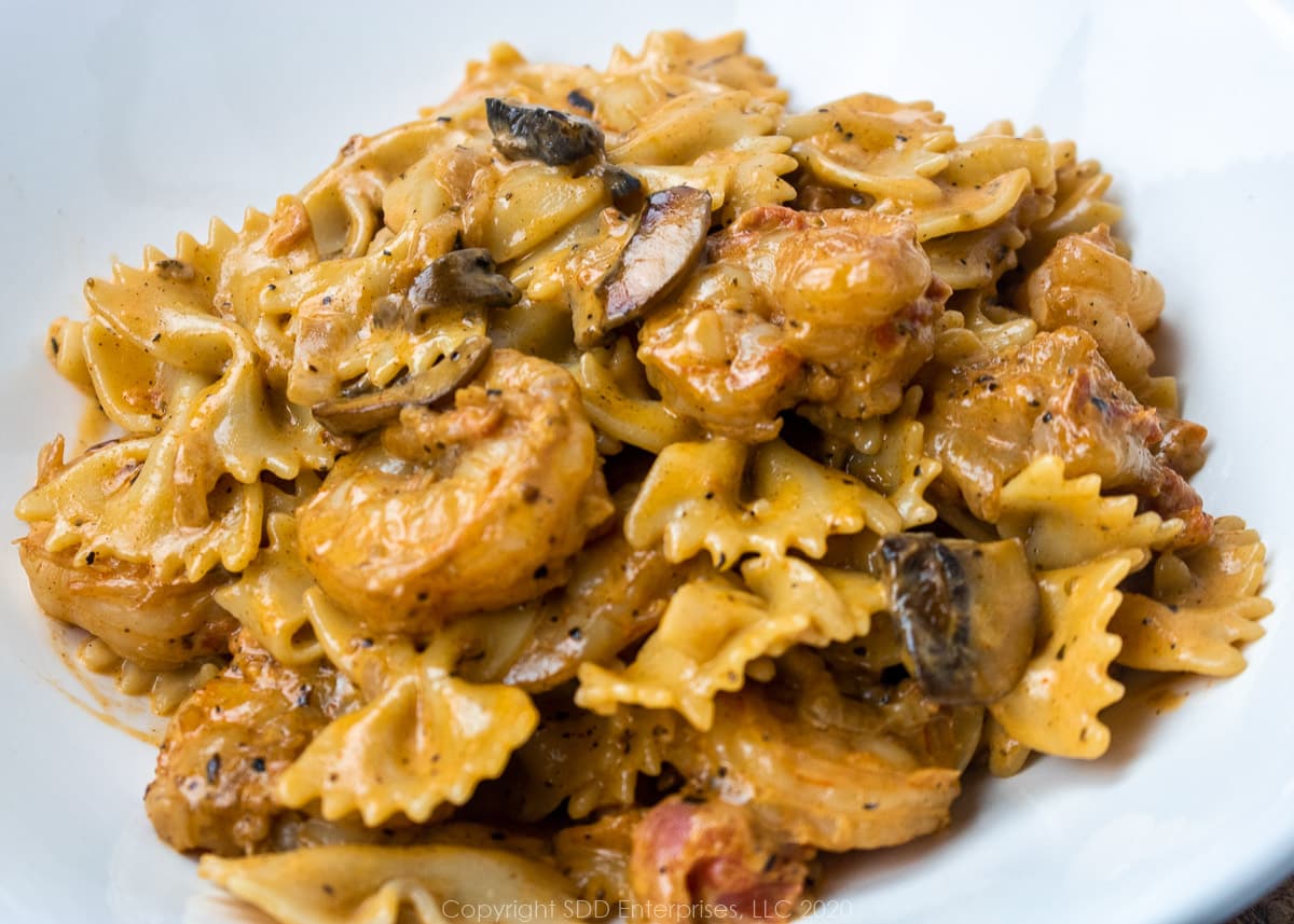 shrimp with pasta in a creamy mushroom sauce in a white bowl