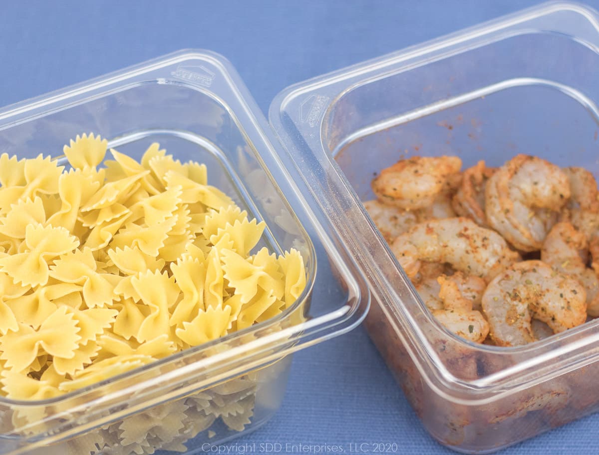 dry bowtie pasta and seasoned shrimp in bowls for creamy shrimp pasta