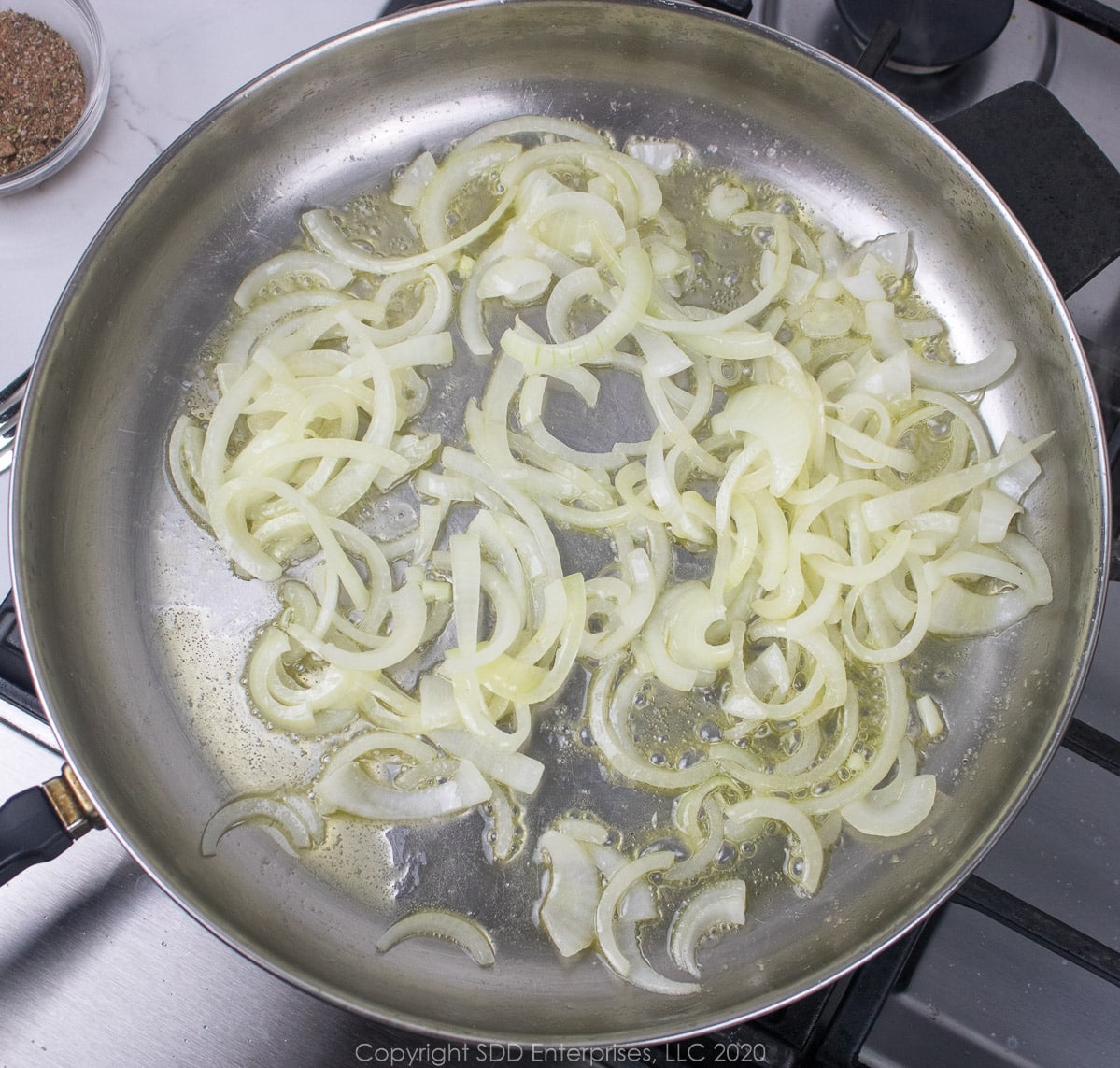 sliced omions sauteing in a frying pan