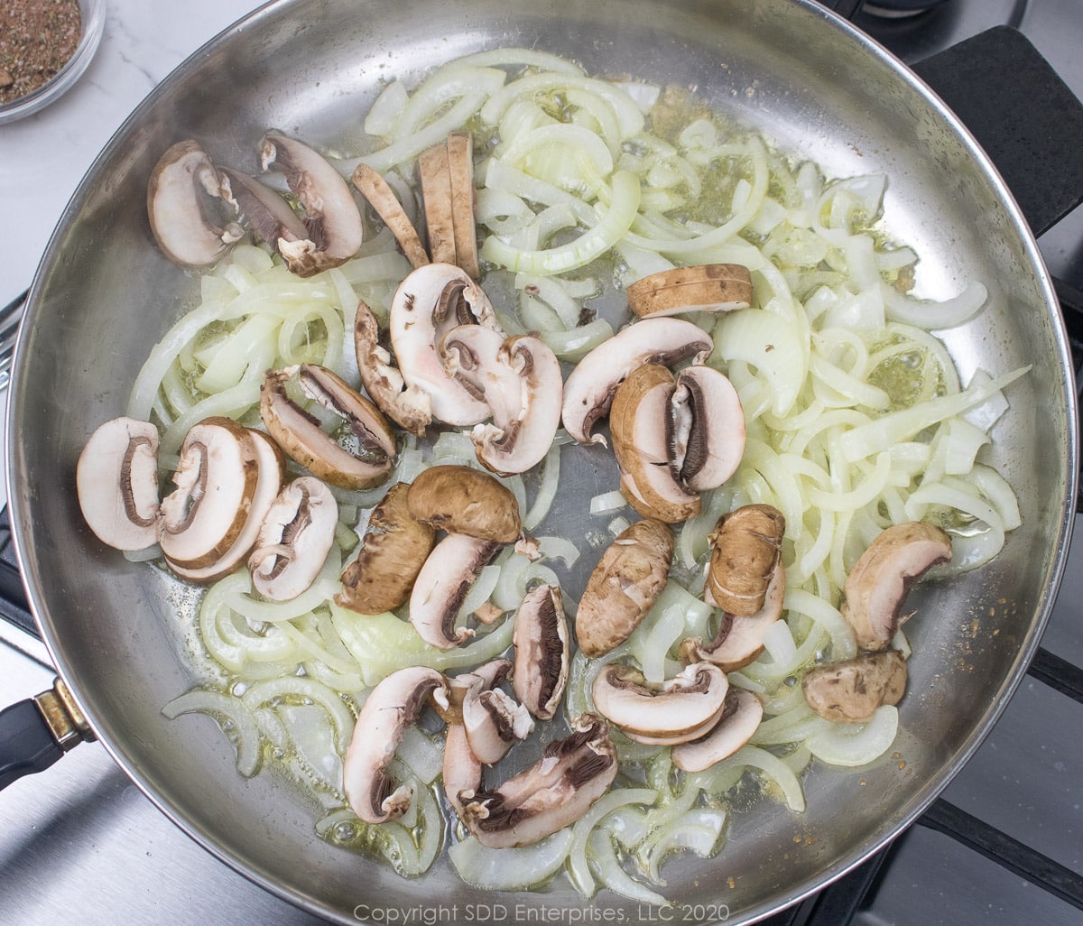 sliced mushrooms with onions in a frying for creamy shrimp pasta