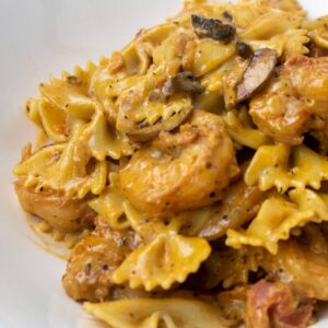 shrimp with pasta in a creamy mushroom sauce in a white bowl