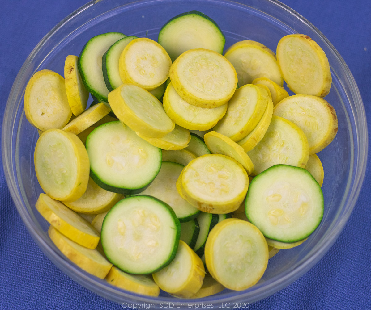 sliced fresh yellow squash and zucchini in a glass bowl