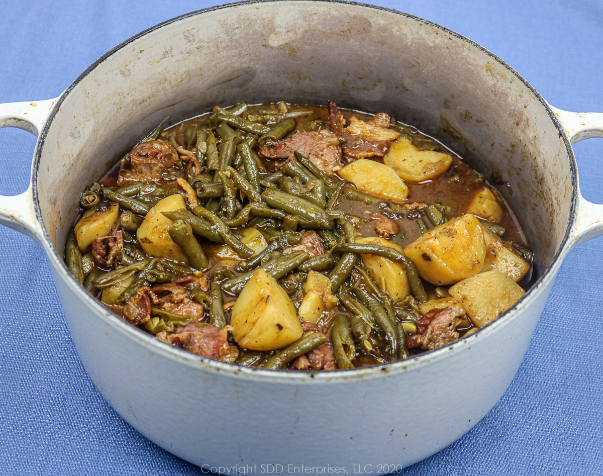 smothered green beans with potatoes and ham in a dutch oven