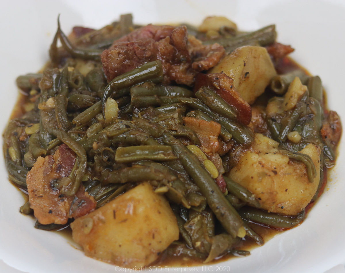 green beans smothered with potatoes, ham and bacon in a white owl