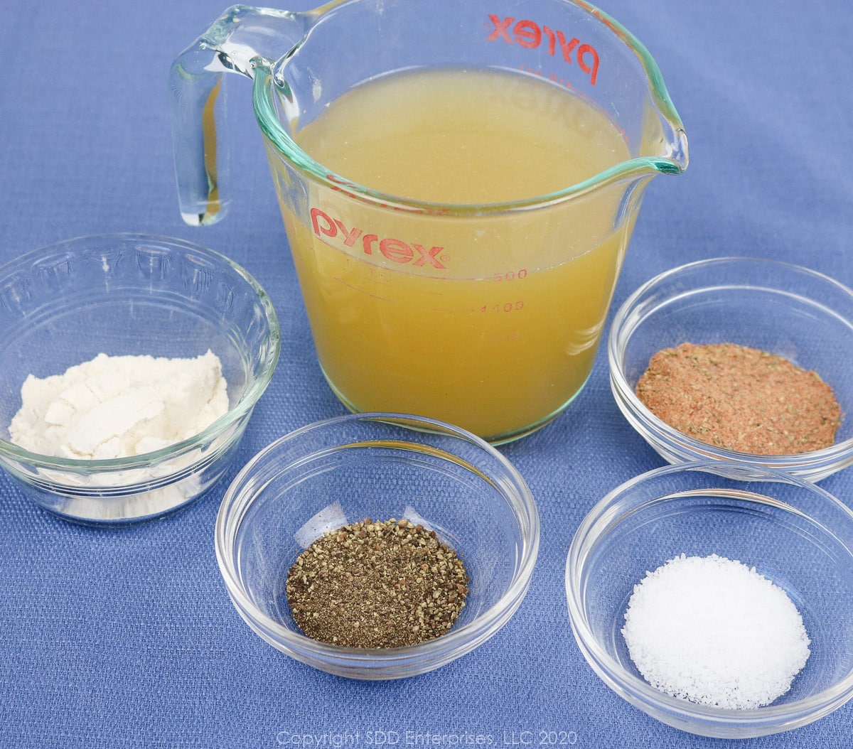 flour, kosher salt, black pepper and creole seasoning in prep bowls and chicken stock in a measuring cup