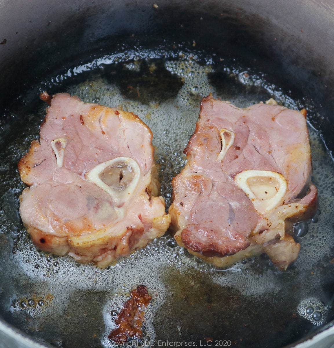 smoked ham shanks being seared in a dutch oven