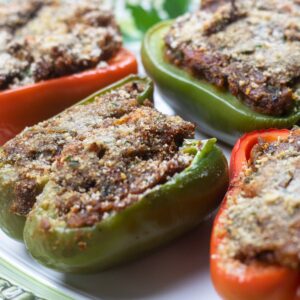 red and green bell pepper half's stuffed with crawfish on a green trimmed platter